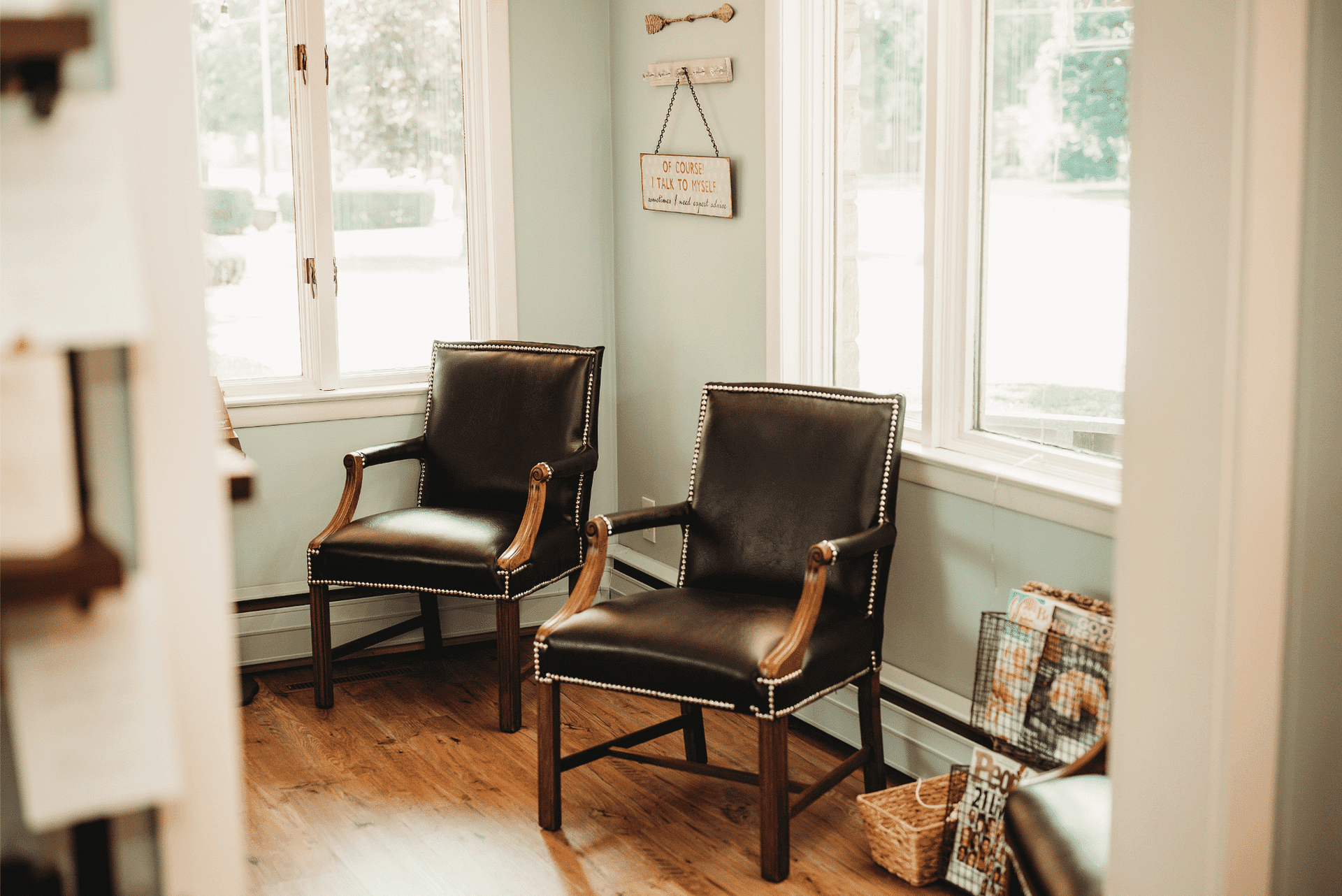 Two leather chairs in a bright room with windows and light green walls.