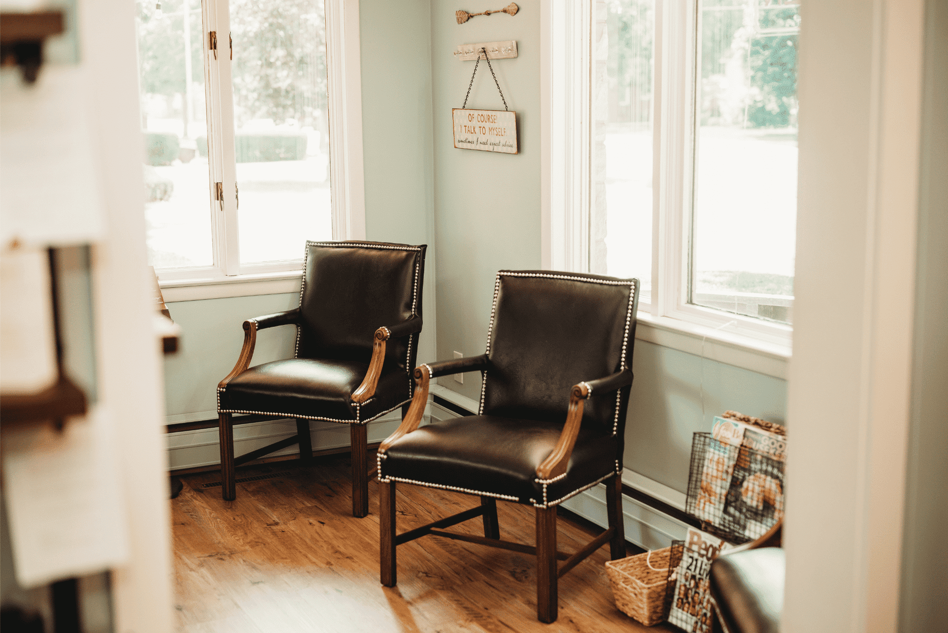 Two leather chairs in a bright room with windows and light green walls.